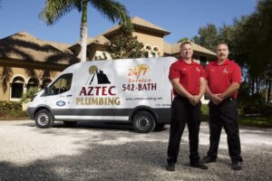 Two Aztec plumbers standing in front of a service van