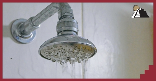 A rain shower head attached to a wall and releasing water