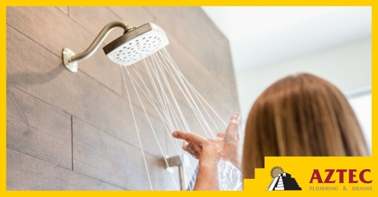A woman holding her hands up to a running showerhead
